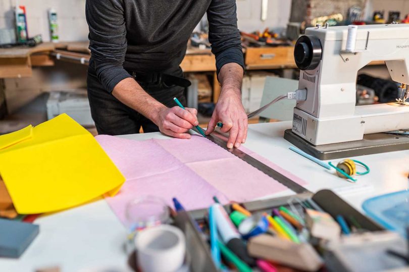 designer marking pink fabric with ruler