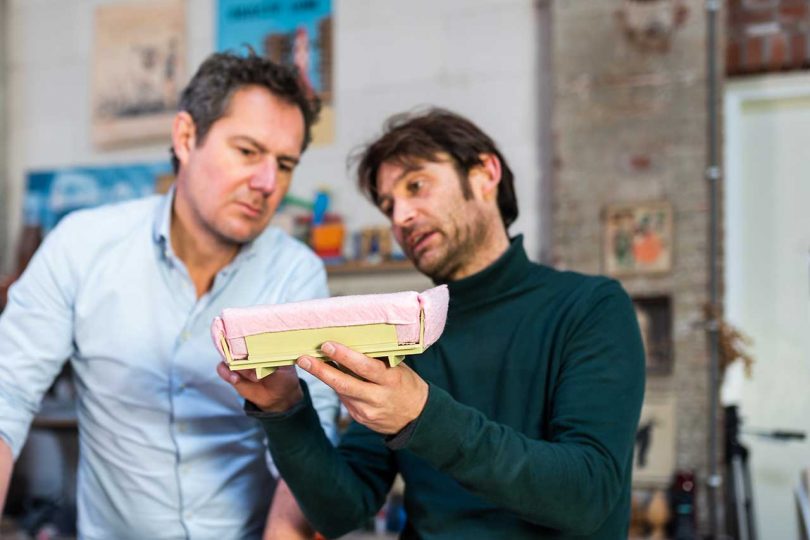 two men looking at miniature sofa prototype