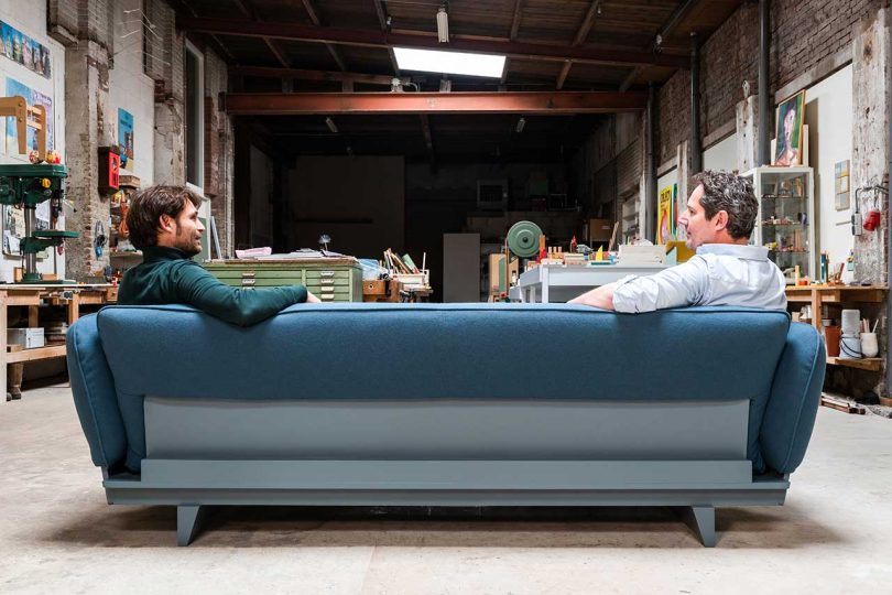 back of blue sofa with two men sitting on it