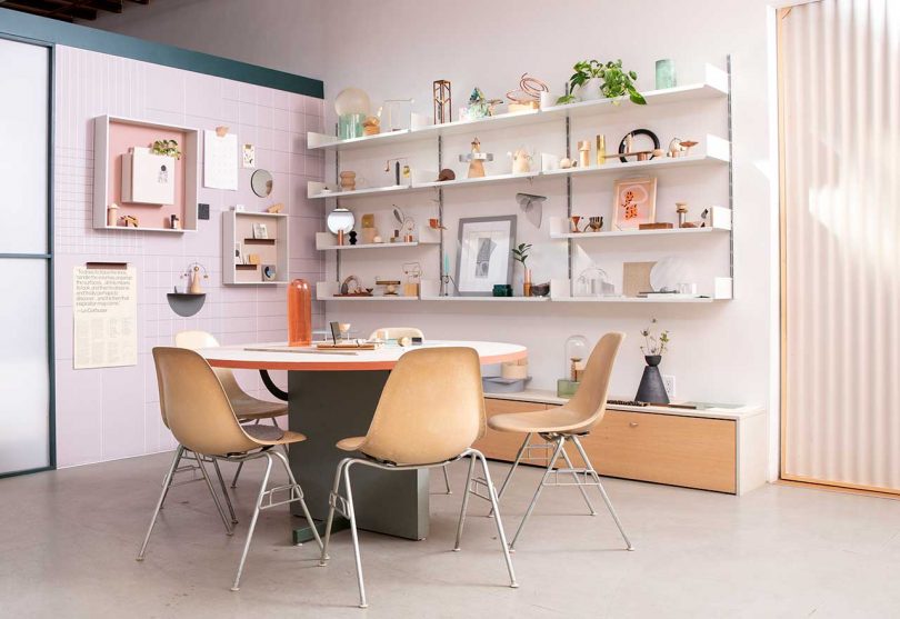 modern workspace with shelves holding trinkets and a table with chairs