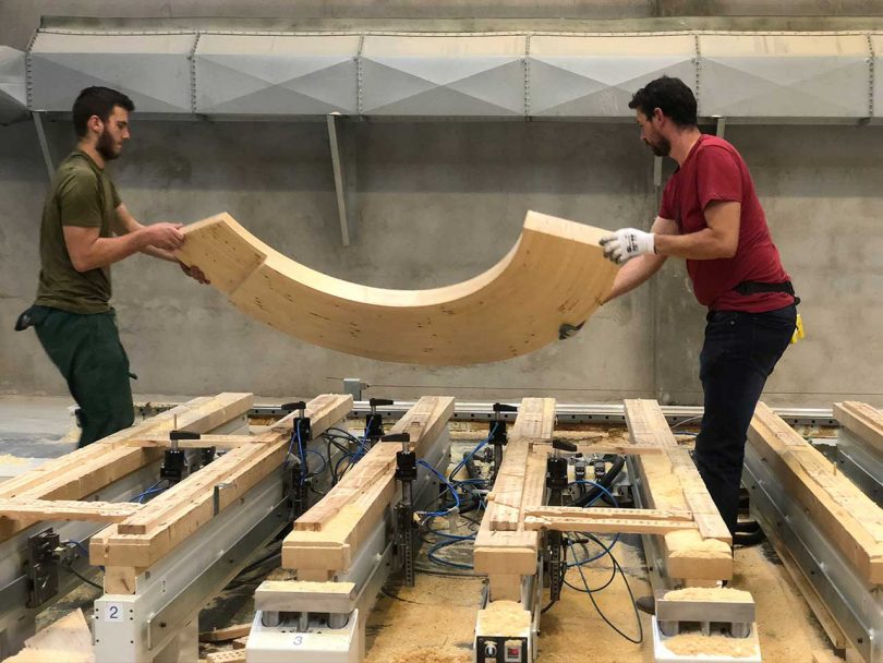 two men moving section of wooden bench