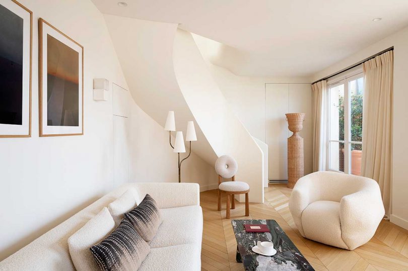 modern living room in shades of white and cream with curved staircase