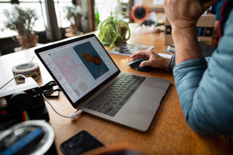 laptop open on desk with person viewing while using mouse