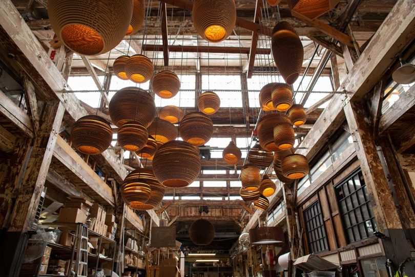 many brown cardboard light pendants hang in workshop