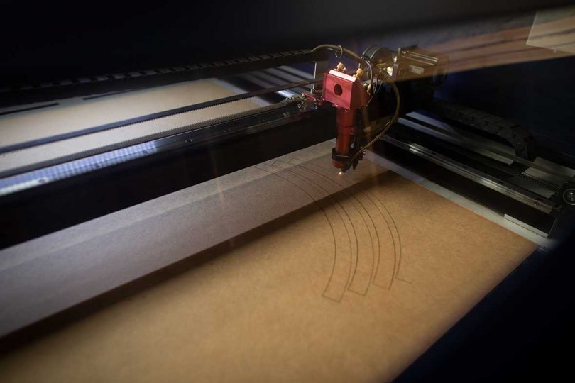 closeup of laser cutter cutting curved bands of cardboard