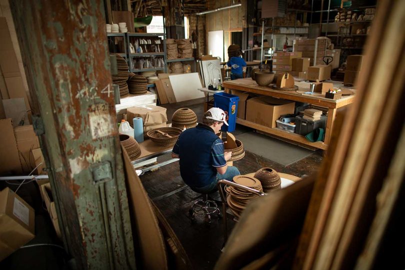 worker assembles cardboard bands into light fixtures