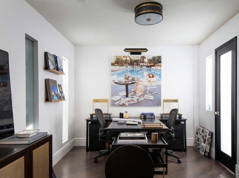 modern office with double sided black desk and chairs with artwork of faye dunaway overhead