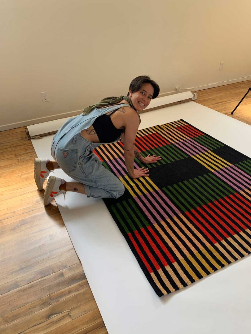 PERSON IN OVERALLS KNEALING ON TOP OF BRIGHT RUG