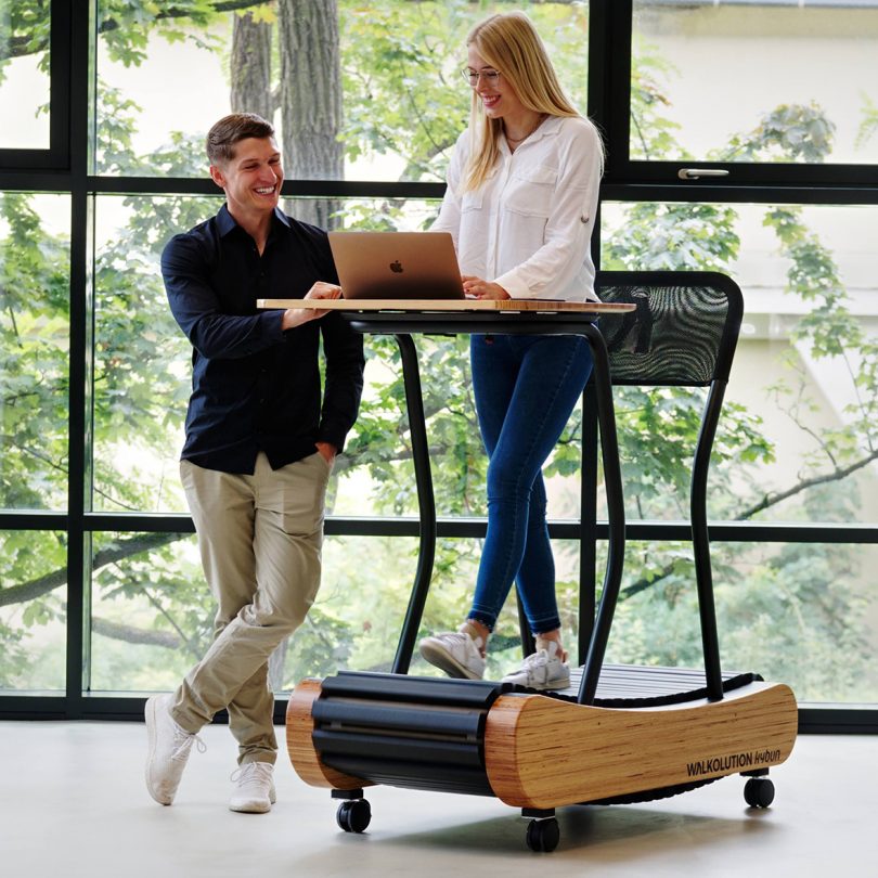 woman standing on treadmill workstation while talking to man standing next to her