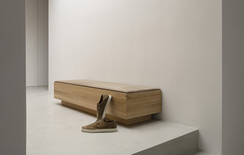 angled view of low wooden bench with pair of shoes