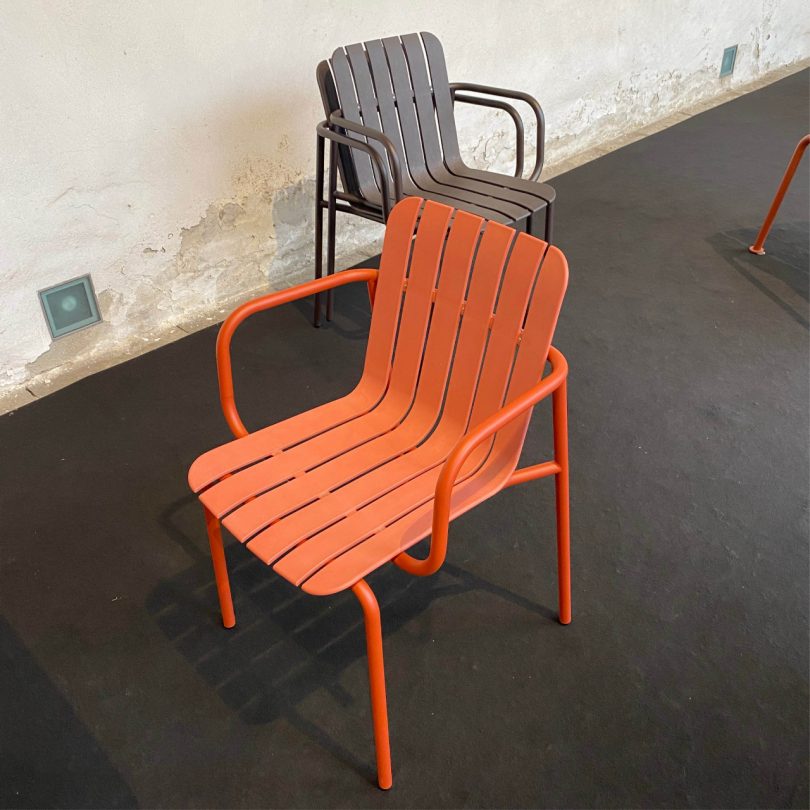 looking down two outdoor slatted chairs, one in orange and the other in grey