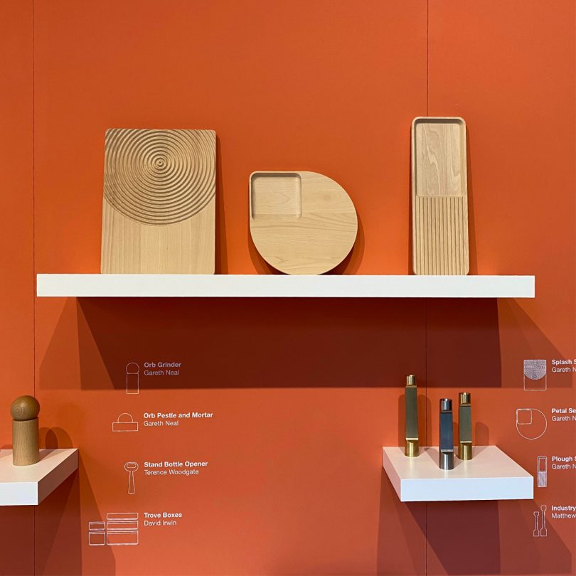 three wooden desk trays with grooves resting on shelf on orange wall