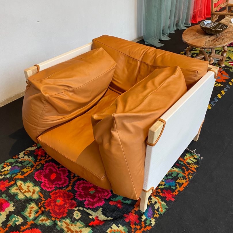 looking down at a chair with wood and white fabric frame and orange upholstered cushions