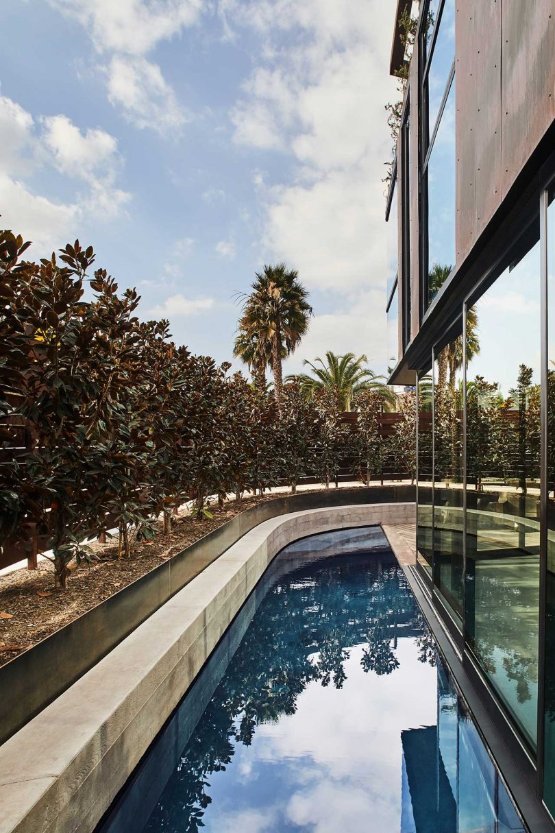 exterior side view of modern glass house with long pool positioned beside it