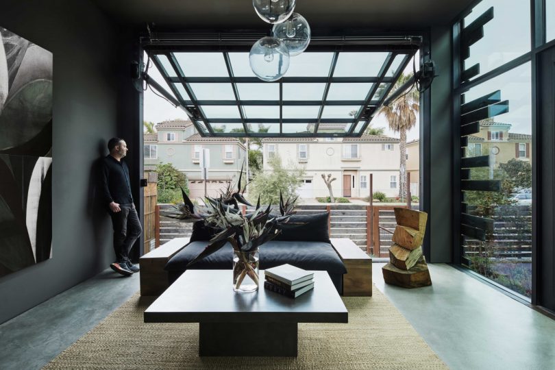 interior of modern seating area of home with garage style door opened and man standing to side