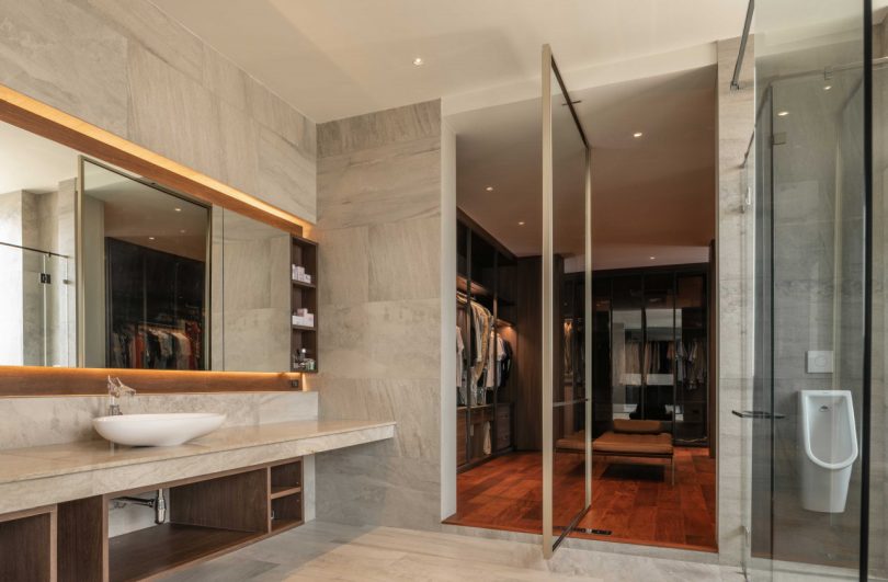 large modern bathroom looking through pivoting door into large closet