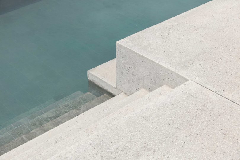 down view of minimalist stairs descending into blue swimming pool