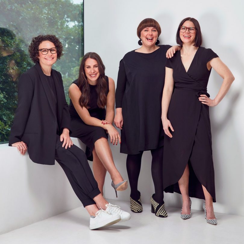 Four women in all black standing together