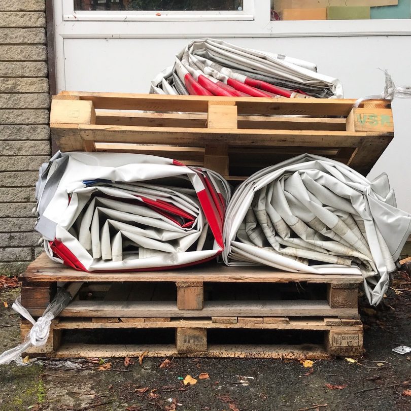 stack of used palettes and rolled up tarps