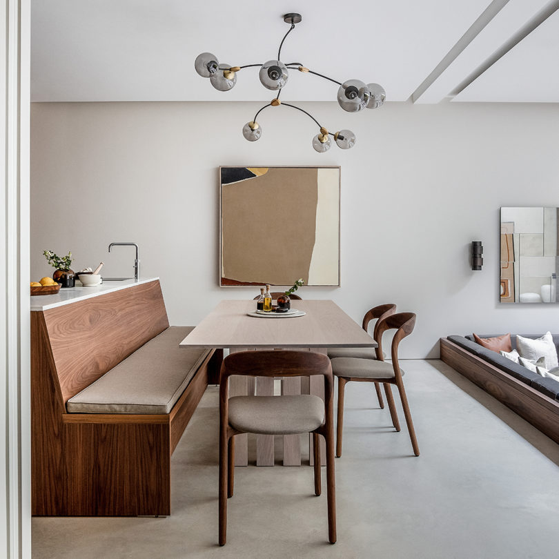 styled interior space of dining table with chairs and bench, artwork, and overhead chandelier lighting