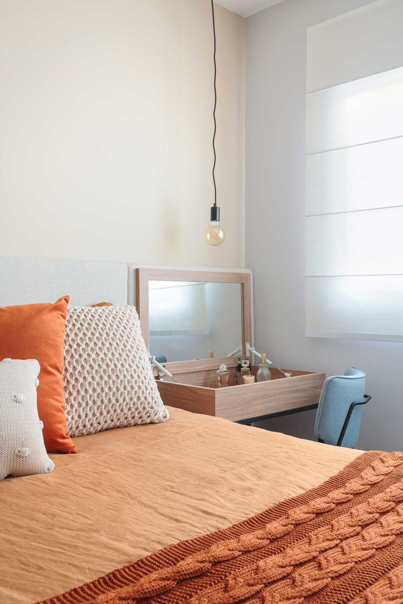 angled view of bedroom with peach bedding and vanity table opened beside bed