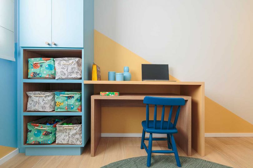 angled view of modern kid's room with graphic blue and peach walls and built-in storage