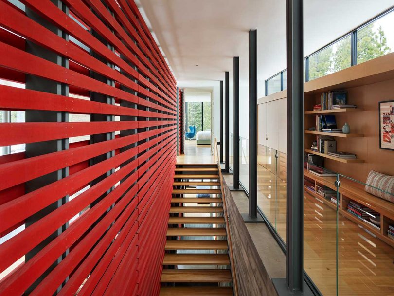 view of upper part of open staircase with open red slatted wall on one side and hallway on other