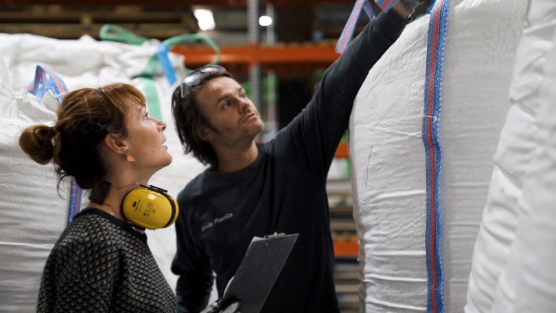 man and woman side views as they look up at bundle of material