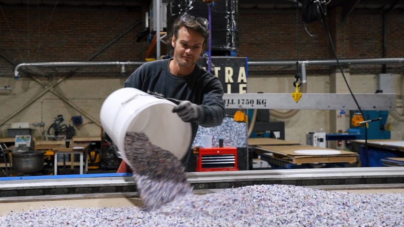 man with bucket pouring recycled plastic bits onto machine