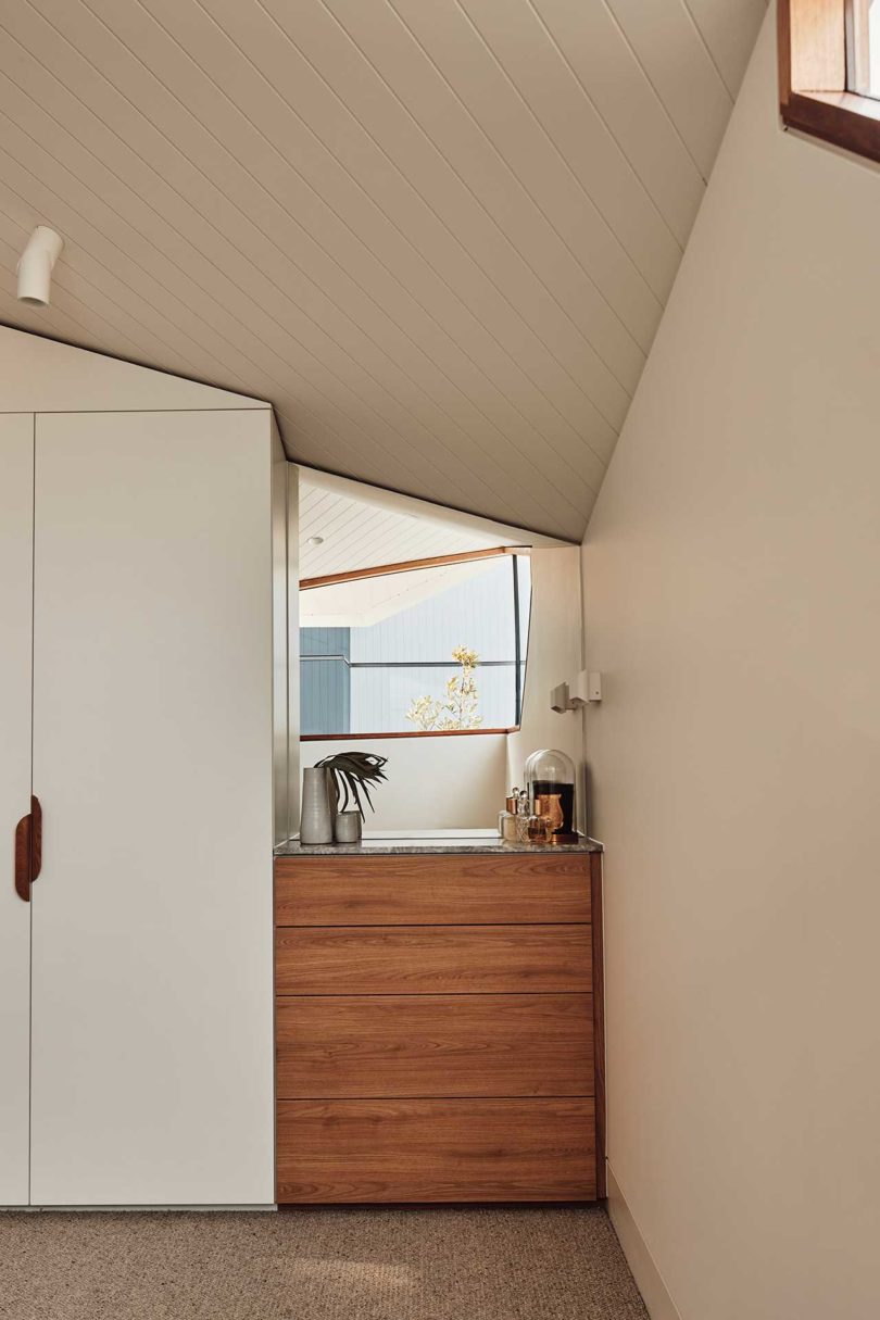 corner of modern bedroom with wood chest of drawers and mirror above