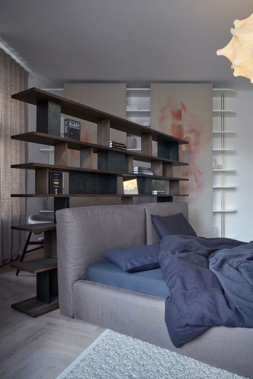 angled view of modern bedroom with bed in front of floating wood shelves