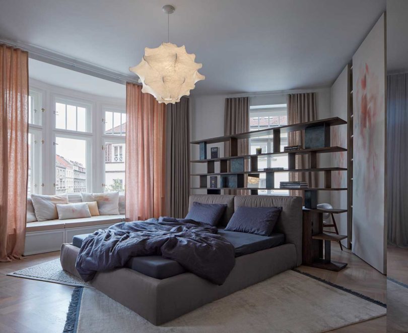 angled view of modern bedroom with bed in front of floating wood shelves