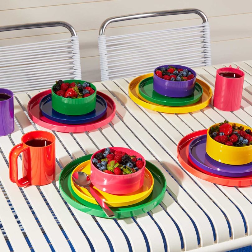 angled view of white dining table with rainbow colored dinnerware