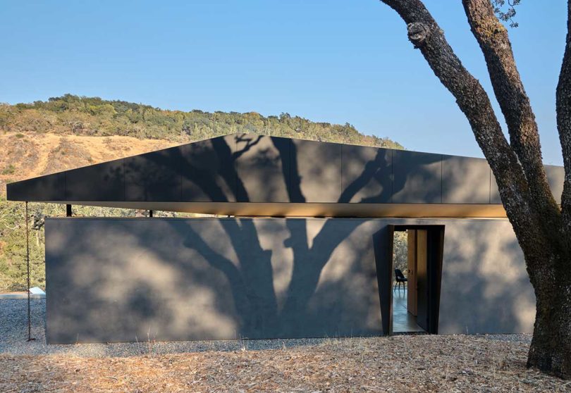 exterior view of small modern black house with door open