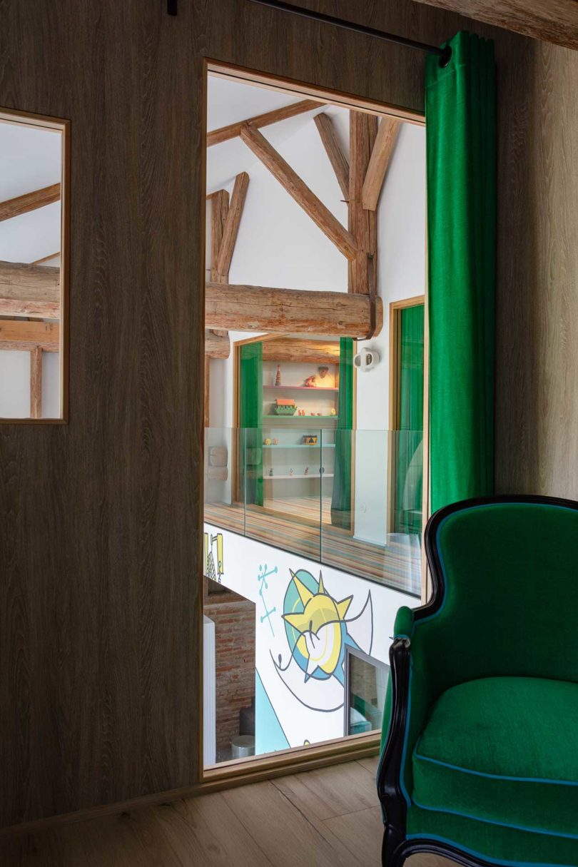 angled view of green chair in room with window looking out to main living space