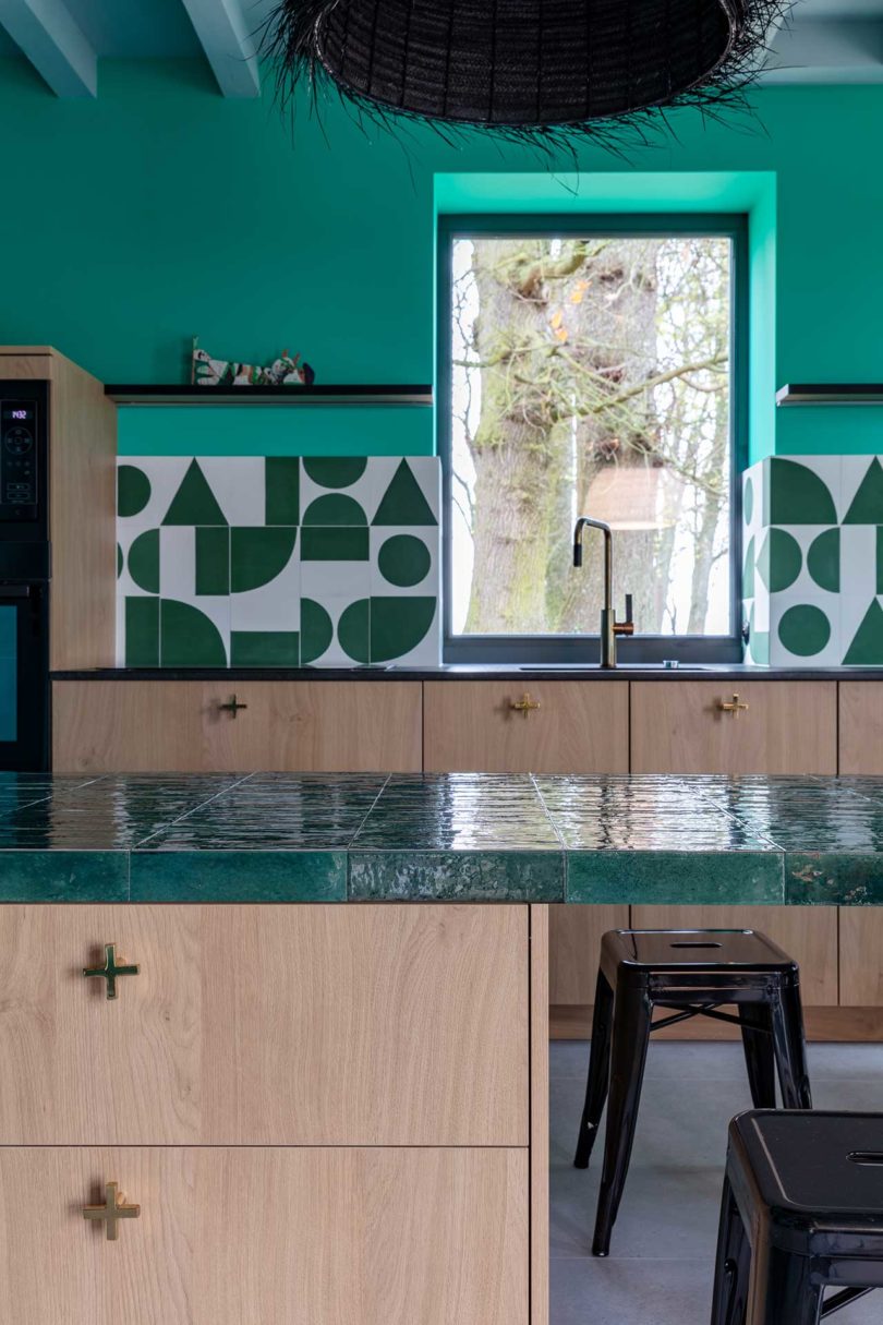 modern renovated kitchen with wood cabinets and turquoise walls with geometric tile