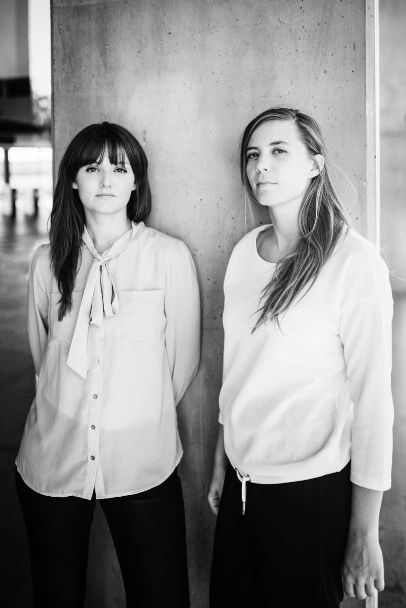 a brunette and blonde woman standing in white shirts