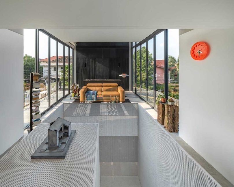 interior shot of modern home top floor open living space flanked by walls of windows