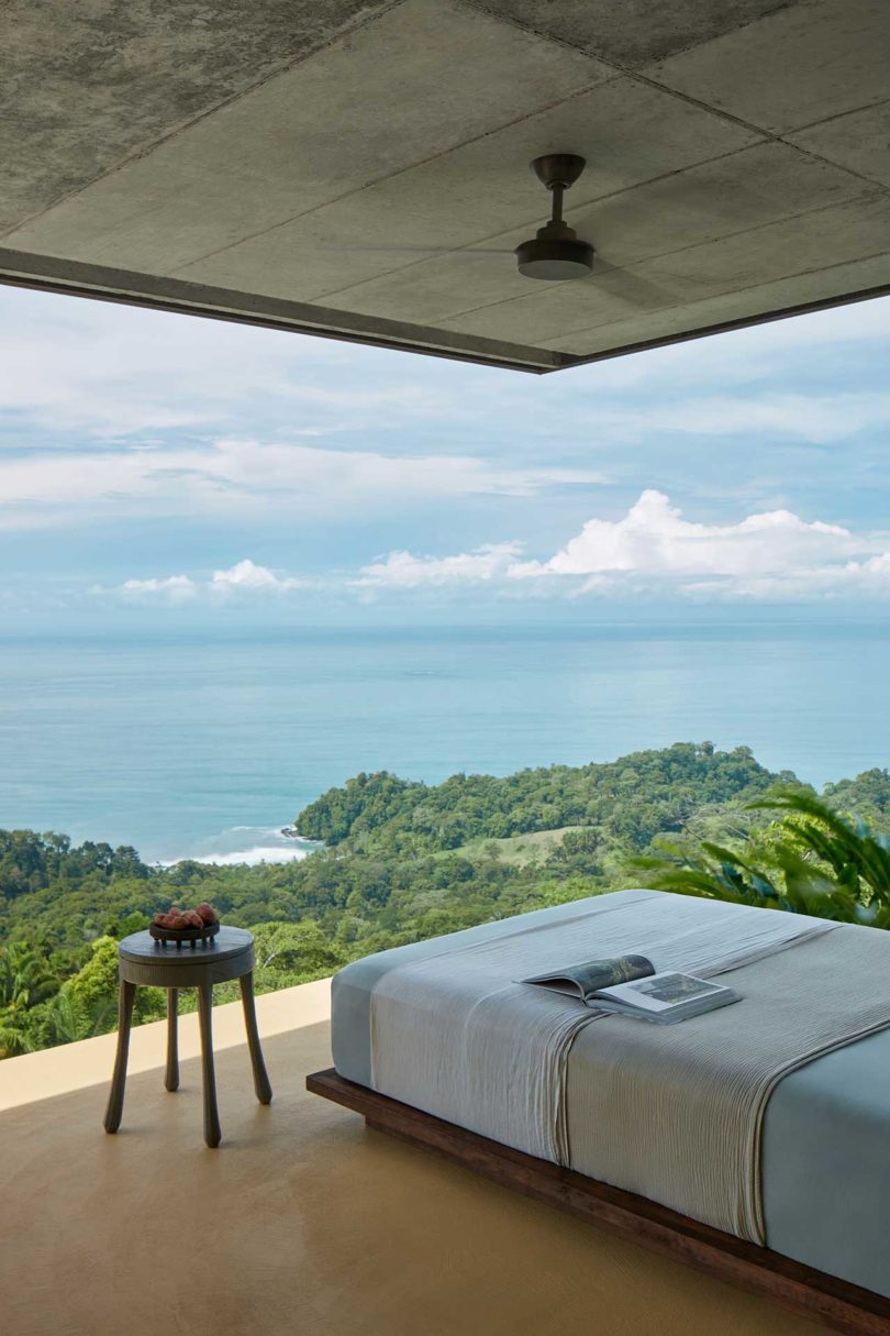 side view of modern bedroom looking out through floor to ceiling windows to green hillside