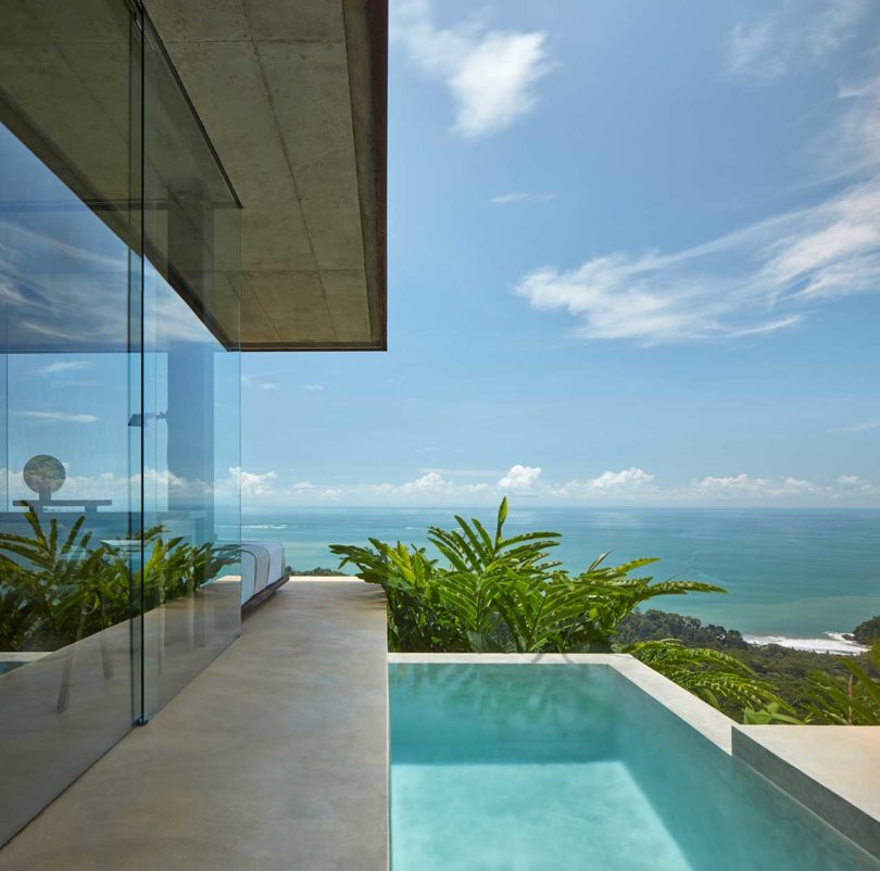 side view of modern villa with built-in pool looking out over hillside and ocean