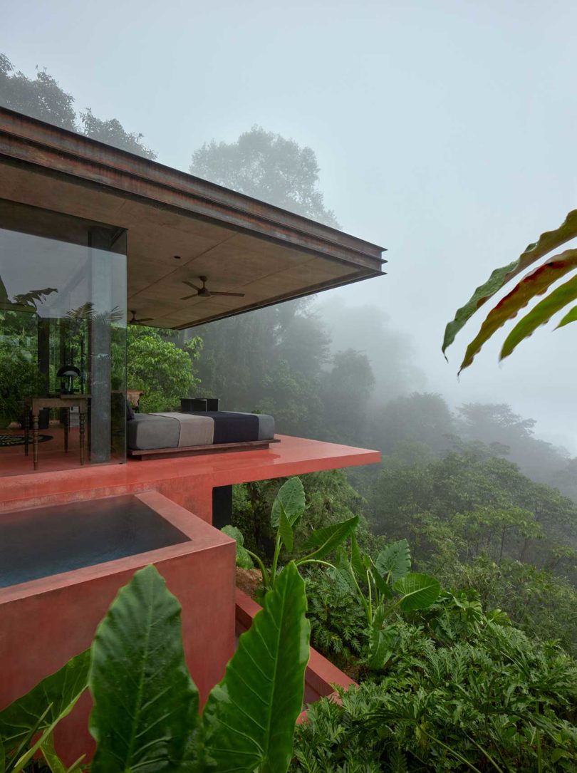 angled side view of modern villa with red floors looking out to tropical landscape