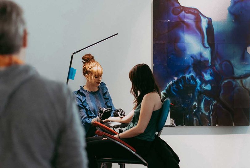 Tattoo artist Amanda Wachob tattooing woman in chair