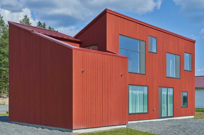 exterior of large modern red house with trees behind it