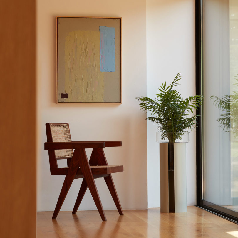 self-watering glass planters on the floor next to a wooden armchair