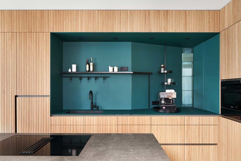 interior shot of modern kitchen with wood slat details and dark green cabinet cutout