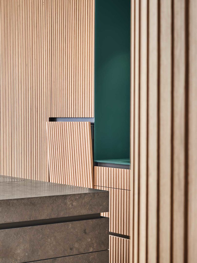 interior shot of modern kitchen with wood slat details and dark green cabinet cutout