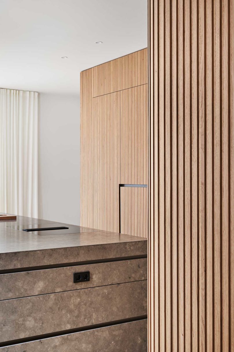 interior shot of modern kitchen with wood slat details and dark green cabinet cutout