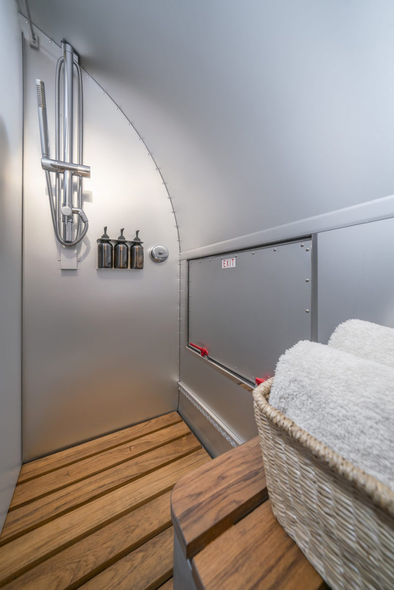 Shower area of Volterra with slatted wood flooring and all-mounted shower gels and shampoo.