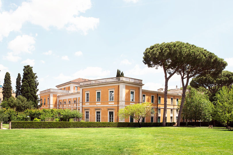 exterior of a yellow brick building surrounded by trees and grass