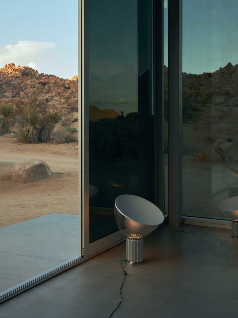 interior shot of small lamp in front of window with rocky landscape beyond